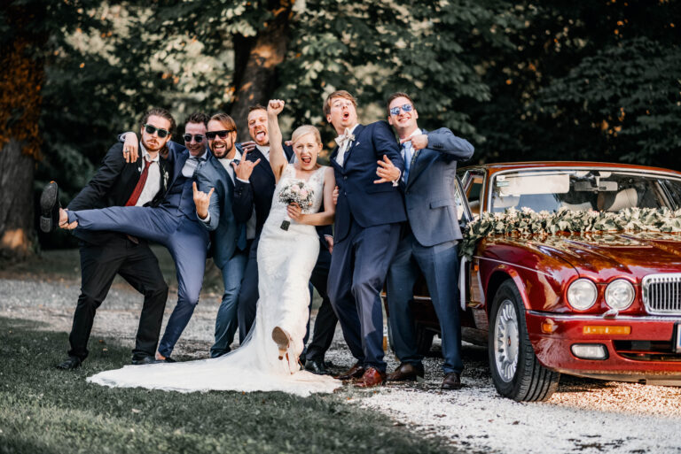 Fröhliches Gruppenfoto – Das Brautpaar mit Freunden bei der Hochzeit