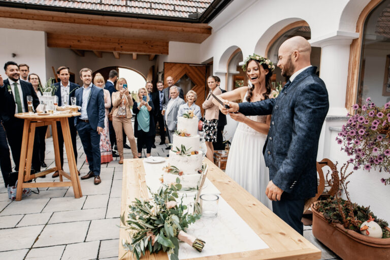 Feierlicher Moment – Das Brautpaar schneidet die Hochzeitstorte im Beisein der Gäste an