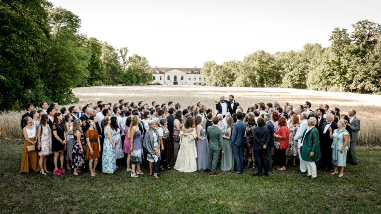 Elegantes Gruppenfoto – Das Brautpaar mit Gästen im Schlossgarten